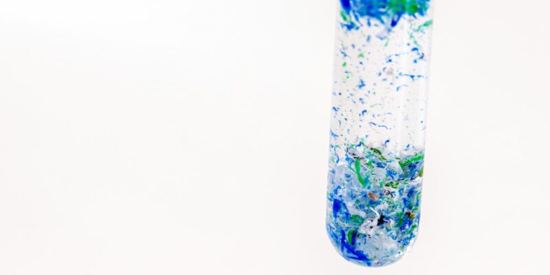 Ein Reagenzglas gefüllt mit Wasser in welchem Mikroplastik enthalten sind, das sind viele kleine Partikel, die unter 5 mm groß sind