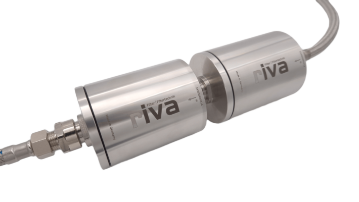 Das Bild zeigt das riva Alva Life Safe Pro Set, bestehend aus einem Aktivkohlefilter und einem Hohlfasermembranfilter. Diese Kombination ist effektiv gegen Schadstoffe und Bakterien im Trinkwasser. Beide Filtergehäuse sind silberfarben und mit dem riva-Logo sowie der Aufschrift "Filtertechnik" versehen, verbunden durch einen flexiblen Schlauchanschluss.